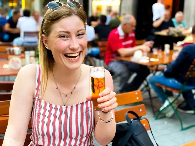 Brauhaus Köln - Brauhaus Em Kölsche Boor. Ein Bild. Zu sehen ist eine Frau mit einem frisch gezapftem Mühlen Kölsch. Sie sitzt draußen auf der Terrasse des Brauhauses in Köln am Eigelstein.